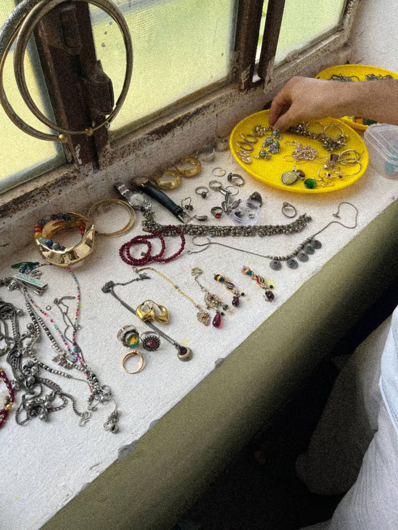 A collection of assorted vintage jewelry, including necklaces, bracelets, rings, and earrings, spread out on a white windowsill.